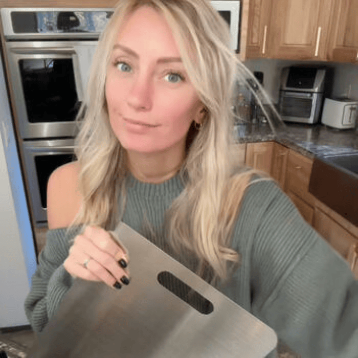 Customer holding a titanium cutting board in a kitchen